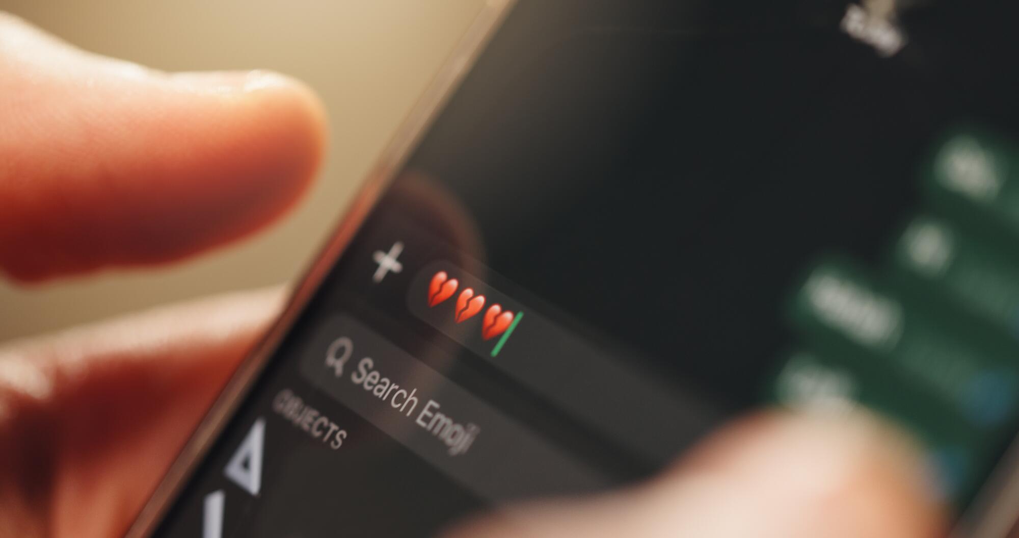 phone screen hands or message with broken heart emoji
